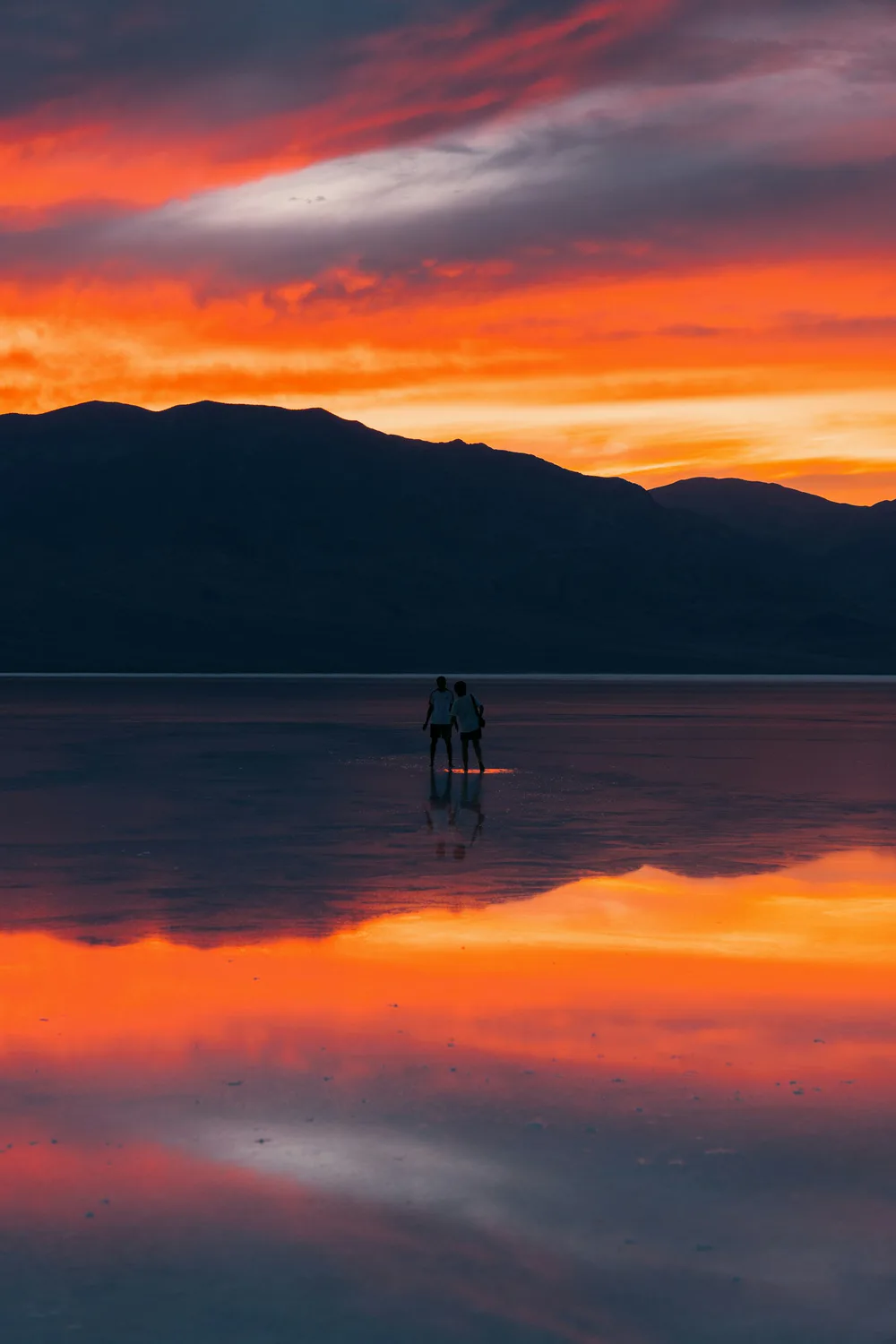 A couple standing together on a reflective landscape at sunset